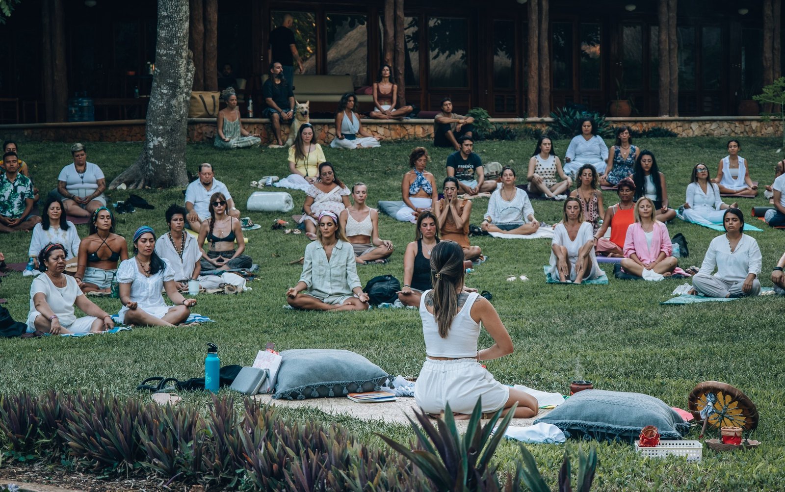 Tatiana Romero sentada en el pasto frente a un grupo de personas meditando en un jardín